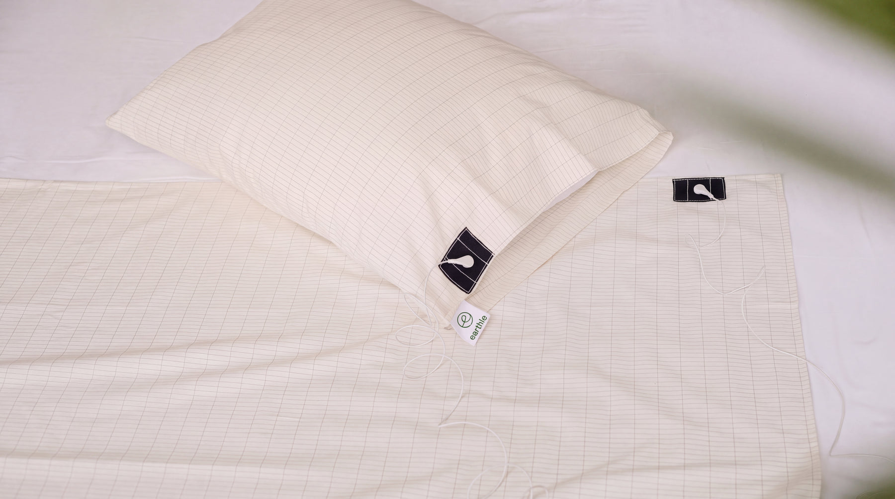 Sábana y funda de almohada de conexión a tierra con la cuadrícula de hilo de plata sobre una cama hecha