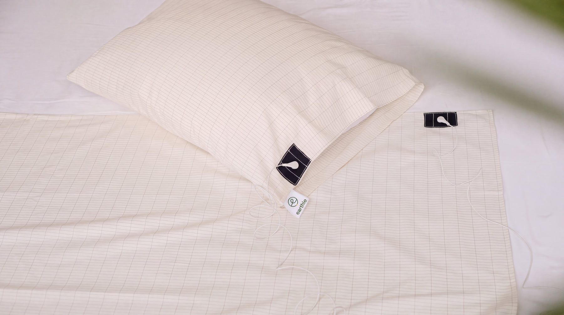 Sábana y funda de almohada de conexión a tierra con la cuadrícula de hilo de plata sobre una cama hecha