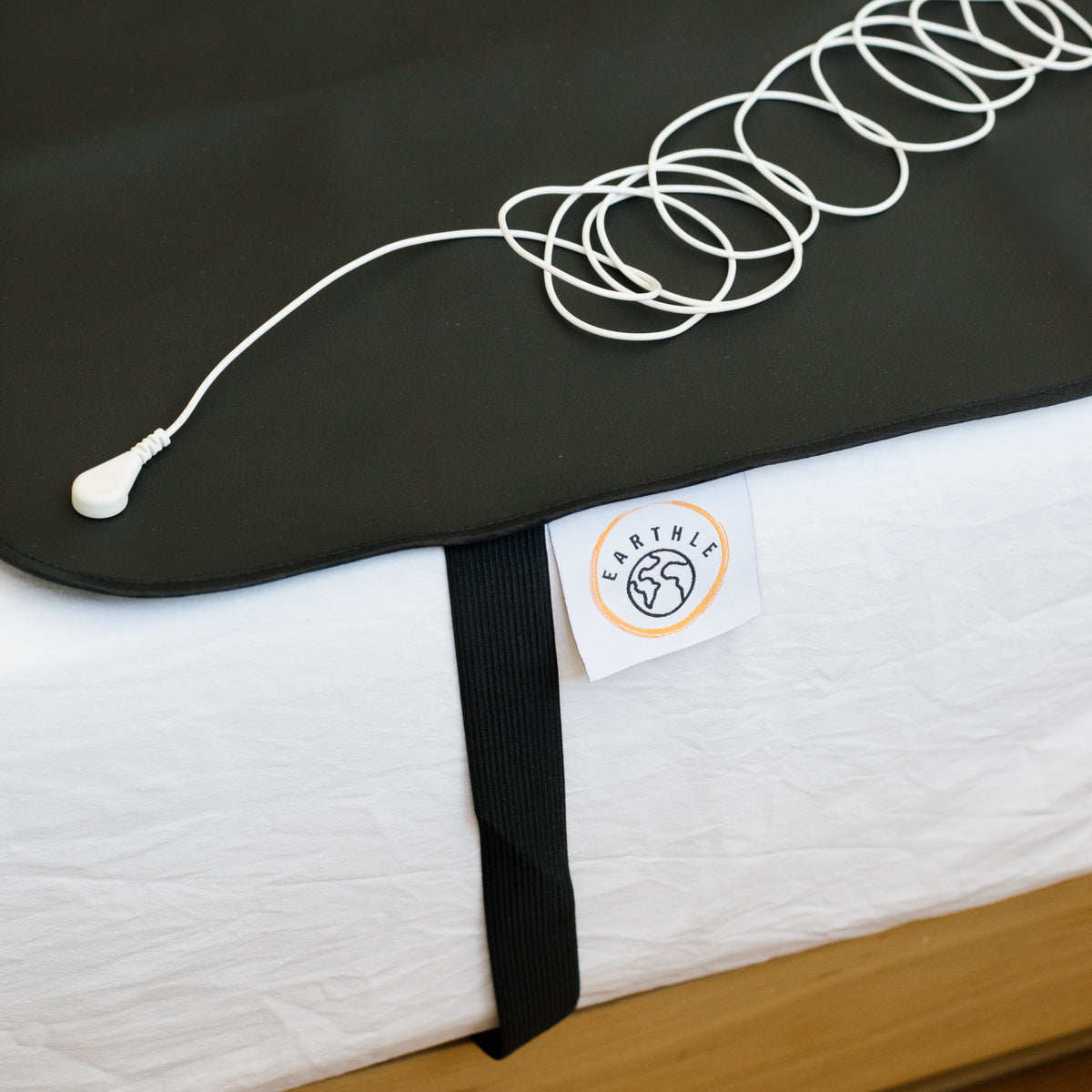 Cable de conexión a tierra enrollado sobre la esterilla negra en una cama hecha