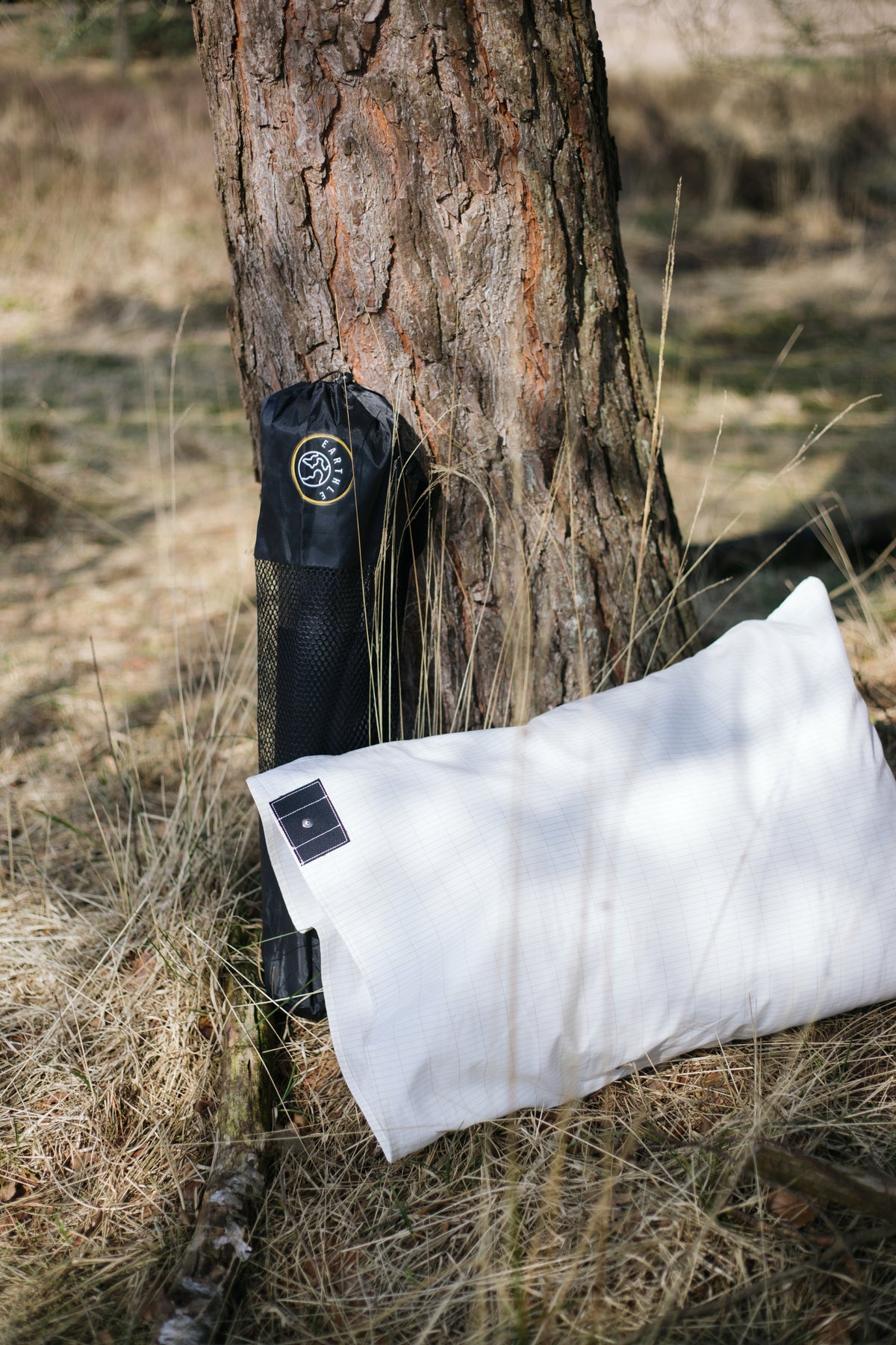 Funda de almohada de conexión a tierra Earthle con su bolsa contra un tronco de pino en el bosque