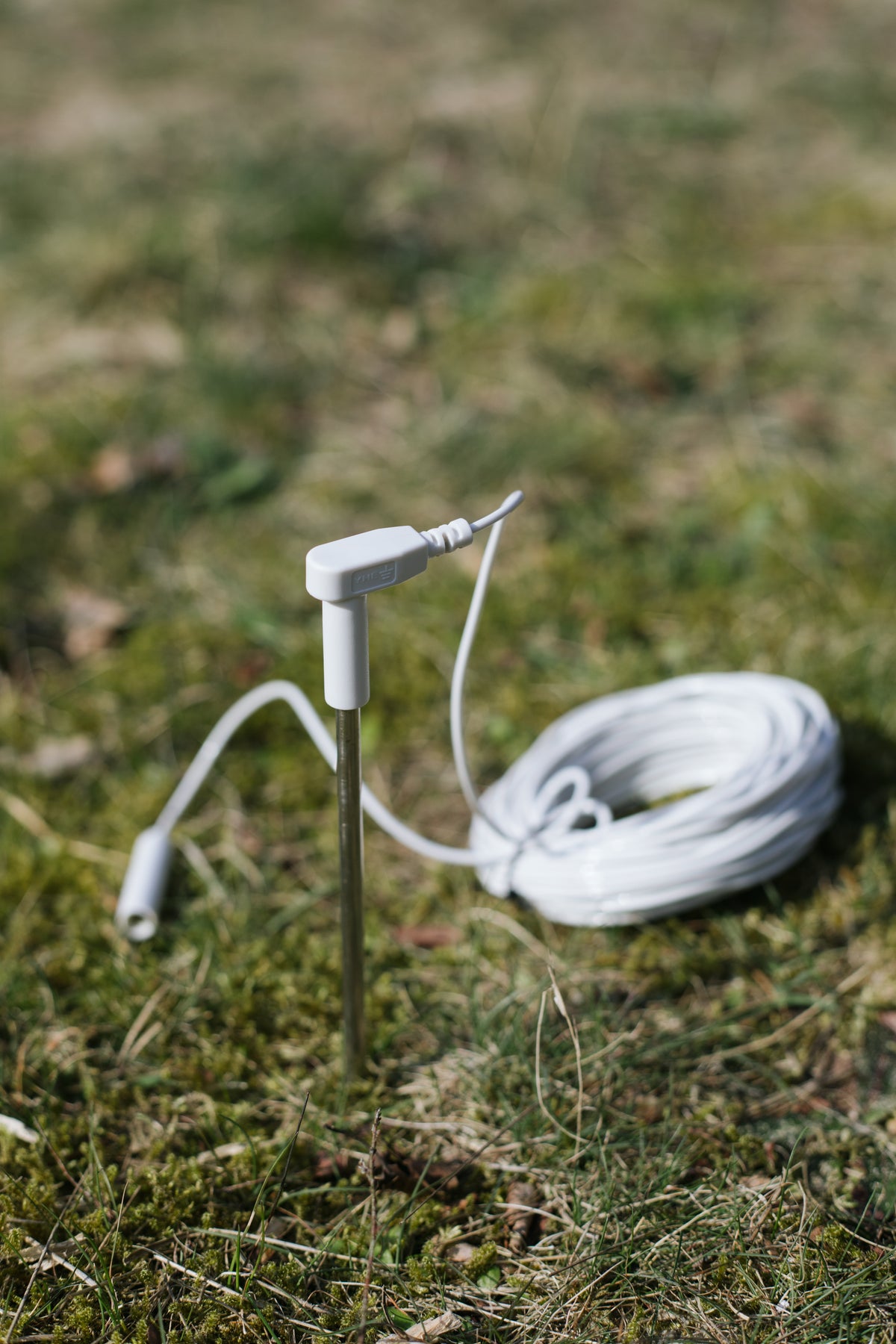 Piqueta de tierra Earthle clavada en el suelo, con el cable enrollado al lado